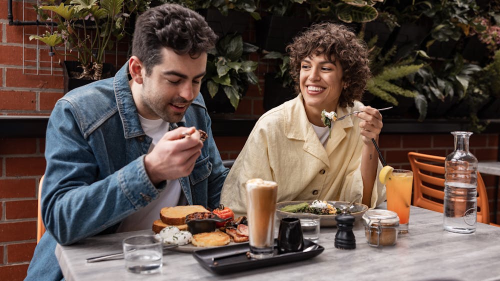 Two guests enjoying brunch and coffee in the courtyard at Webster's MArket and Cafe.