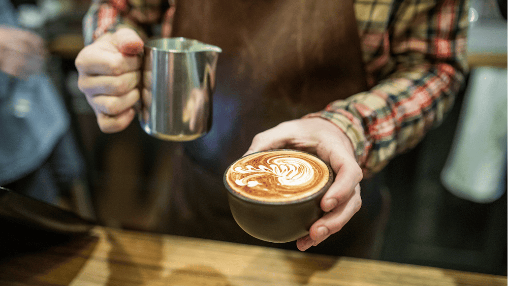 Barista pouring lattee art into a cup of specialty coffee at Webster's Market and Cafe.