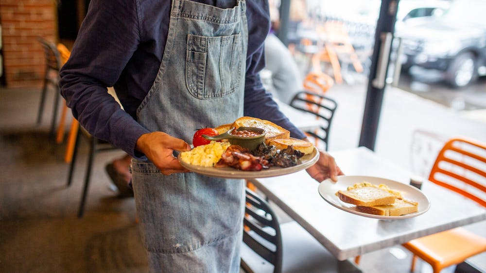 Staff member serving freshly prepared brunch dishes at Webster's Market and Cafe.