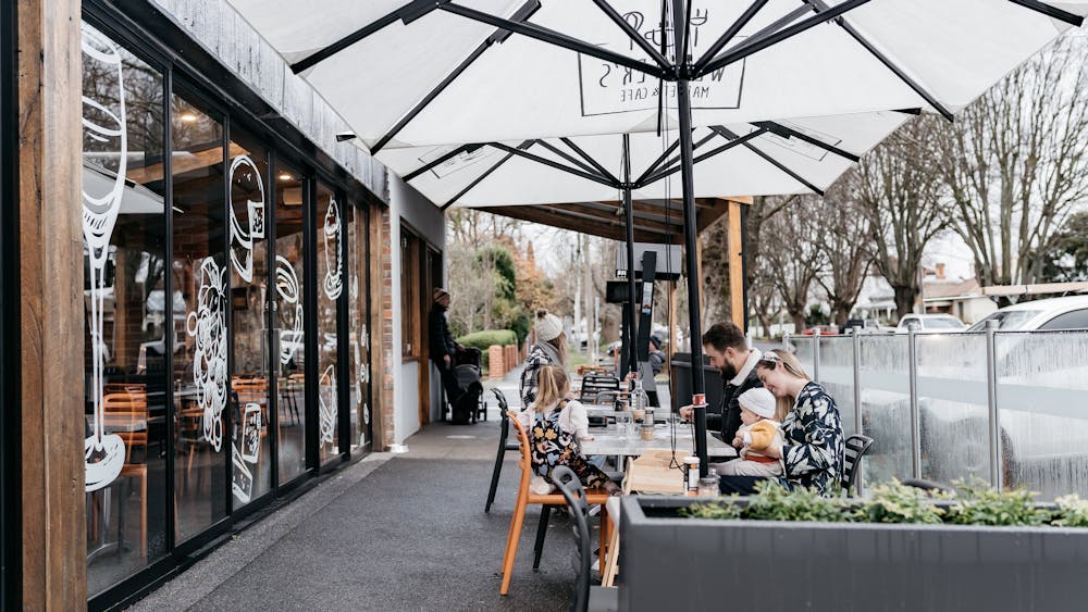 Outdoor seating at Webster's Market and Cafe on tree lined Webster Street.