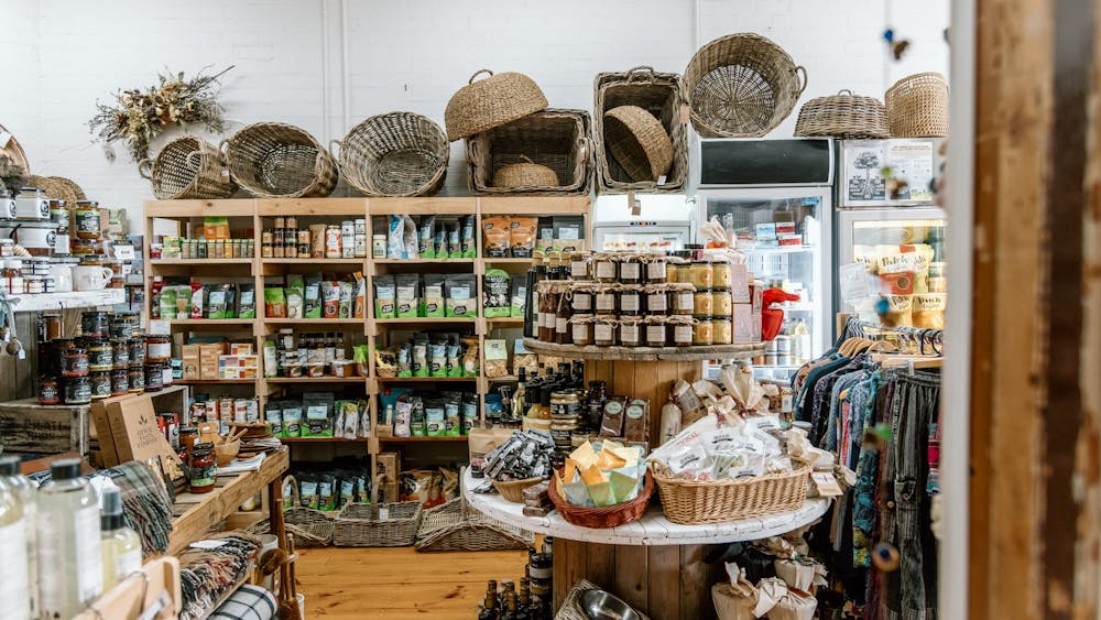 Shelves full of organic groceries, local preserves and cane baskets on top of the shelf.