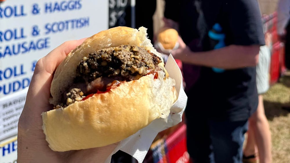 Photographer holds a Haggis Burger in foreground of Mowatts Scottish food stall