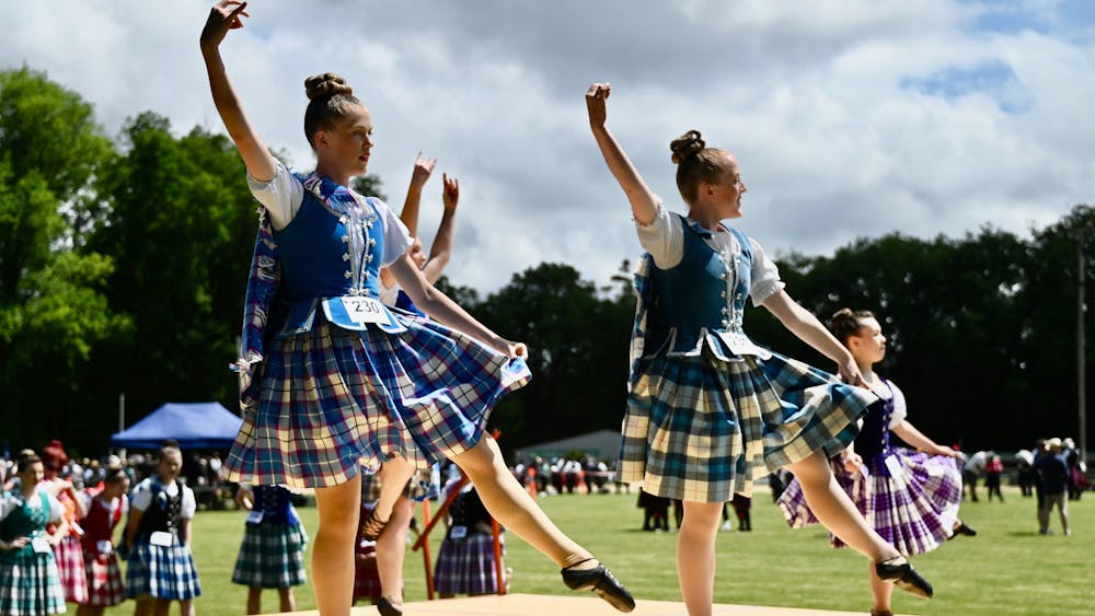 Two female highland dancers in colourful kilts performing a traditional highland fling