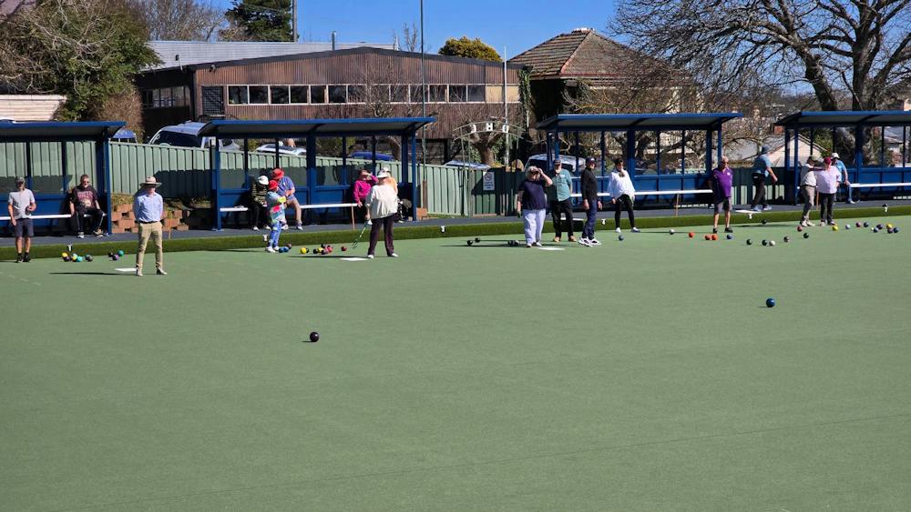 People bowling  on a new synthetic bowling green on a sunny day.