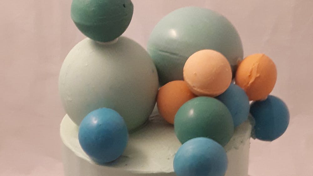 Blue and white iced cake with chocolate balls in blue, green and orange tones and of varying sizes