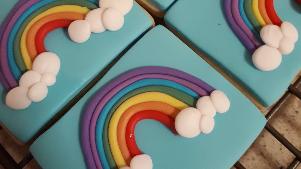 Four iced biscuits with rainbow and clouds on each biscuit