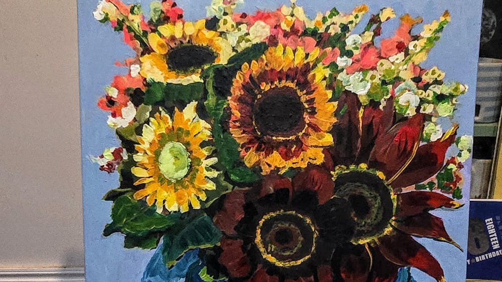 Clear vase with colourful sunflowers and other bright blooms