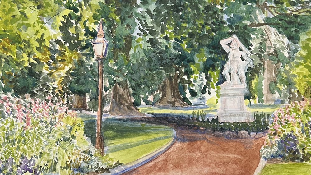 brown path in gardens with marble sculpture and overhanging trees on a sunny day