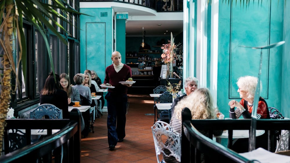 Waiter walking down café with plates of food for customers