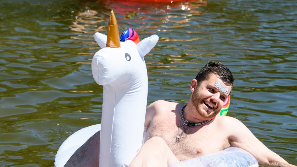 Man smiles in unicorn floaty in Lake Daylesford.