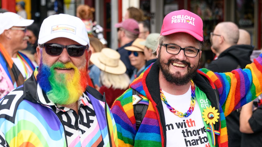 Two people in rainbow colours marching in a parade.